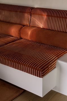 a brown and white striped couch sitting on top of a wooden floor next to a wall