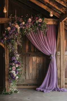 a purple drape draped over a wooden structure with flowers and greenery on it