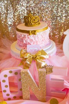 a pink and gold birthday cake with the letter n on it's tiers