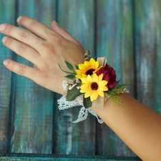 a woman's hand wearing a bracelet with sunflowers and lace