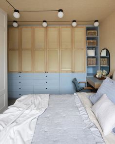 a bedroom with blue and white bedding, built - in bookshelves and cabinets