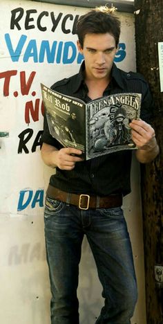 a man reading a book in front of a sign