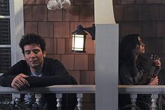 two people sitting on a porch with their arms crossed and looking at something in the distance