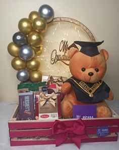 a teddy bear sitting on top of a wooden crate filled with chocolates and balloons