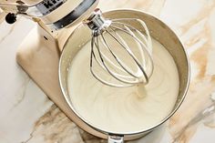 a whisk in a metal bowl on top of a counter next to a mixer