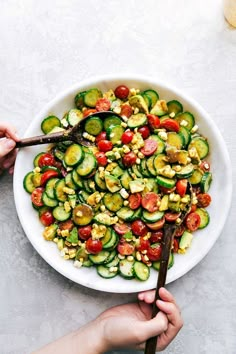 a white bowl filled with cucumber and tomato salad on top of a table