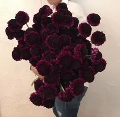 a woman holding a bunch of purple flowers