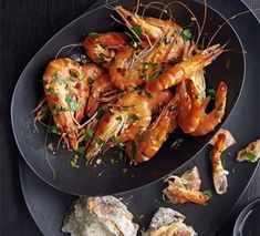 some shrimp and bread on a black plate