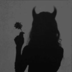 the shadow of a woman holding a flower in her hand and an animal head on it's back