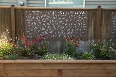 a wooden planter filled with lots of flowers next to a fenced in area