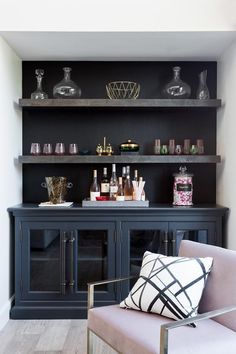 a bar with bottles and glasses on top of it, next to a gray chair