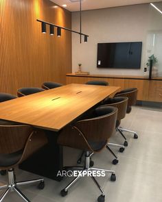 an empty conference room with chairs and a large wooden table in front of a flat screen tv