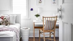 a bedroom with white walls and wood floors has a bed, desk, chair, and pictures on the wall