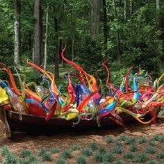 a boat made out of glass sitting in the middle of a forest filled with trees