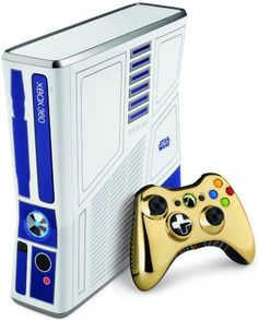 a video game system with a gold controller next to it's case and cover