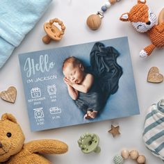 a baby's birth announcement surrounded by stuffed animals and other items on a white surface