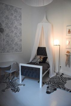 a white bedroom with zebra rugs on the floor and a canopy bed in the corner