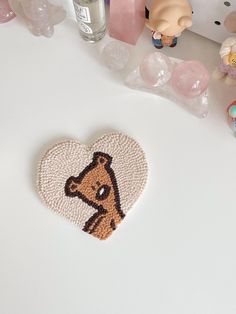 a heart shaped brooch sitting on top of a table next to other figurines