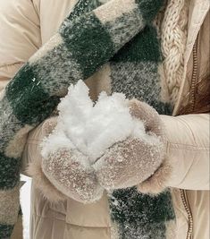 a woman wearing a green and white scarf holding a snowball in her right hand