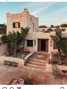 a house that is made out of stone and has palm trees in the front yard