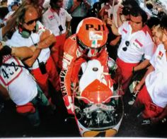 a man riding on the back of a motorcycle next to other men in red and white outfits