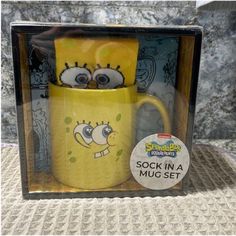 a yellow mug in a box with an image of the face of spongebob on it