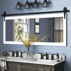 a bathroom vanity with two sinks and a large mirror over it's top, in front of a blue wall