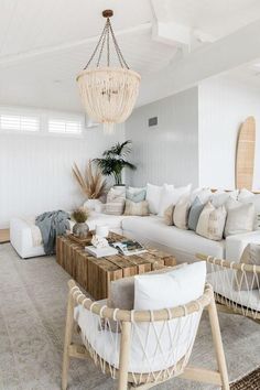 a living room filled with white furniture and a chandelier hanging from the ceiling