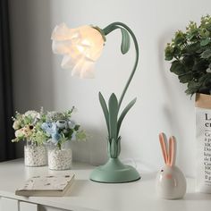 a white table topped with a lamp and flowers