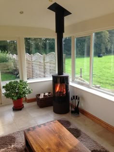 a living room with large windows and a wood burning stove in the middle of it