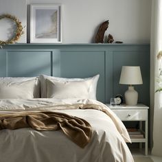 a bed with white linens and pillows in a bedroom next to two framed pictures