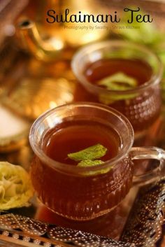 two cups filled with tea sitting on top of a table