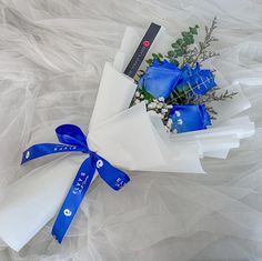 a bouquet of blue roses wrapped in white paper and tied with a ribbon on top