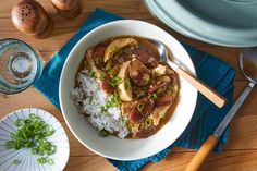 a bowl filled with rice and meat on top of a wooden table next to other dishes