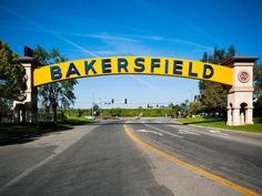 a yellow sign that says bakersfield on the side of a road with trees in the background