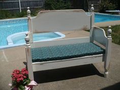 a white bench sitting in front of a pool with flowers on the ground next to it