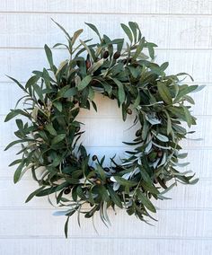 a green wreath hanging on the side of a white brick wall next to a door