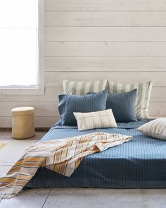 a bed with blue sheets and striped pillows