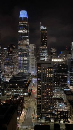 the city skyline is lit up at night, with skyscrapers in the foreground