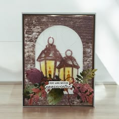 a close up of a card with two lights on it and flowers in the background