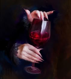 a woman's hand holding a wine glass with red liquid in it, on a dark background