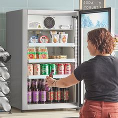 a woman standing in front of a refrigerator filled with drinks