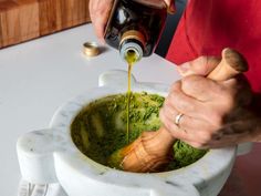 a person pouring olive oil into a white bowl