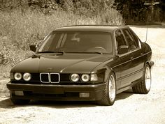 a black car parked on the side of a dirt road