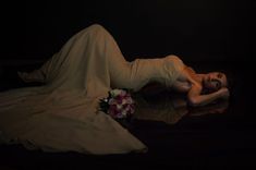 a woman laying on the ground in a white dress