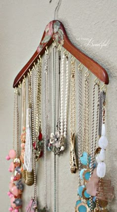 there is a wooden hanger with many necklaces on it