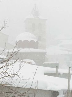 a clock tower is covered in snow on a cloudy day