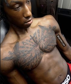 a man with tattoos on his chest sitting in a chair