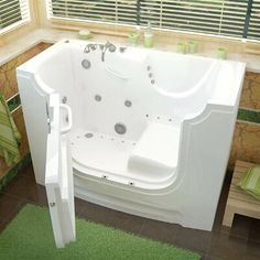 a white bath tub sitting inside of a bathroom next to a green rug on the floor