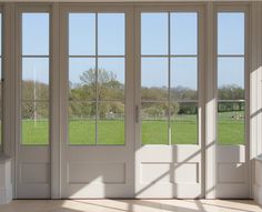 an empty room with large windows and grass in the background